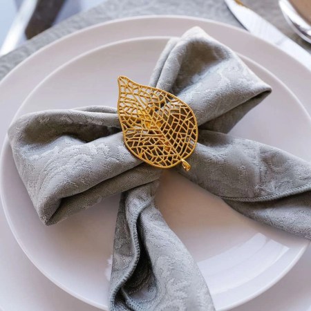 Set of four gold coloured napkin rings in the shape of a leaf